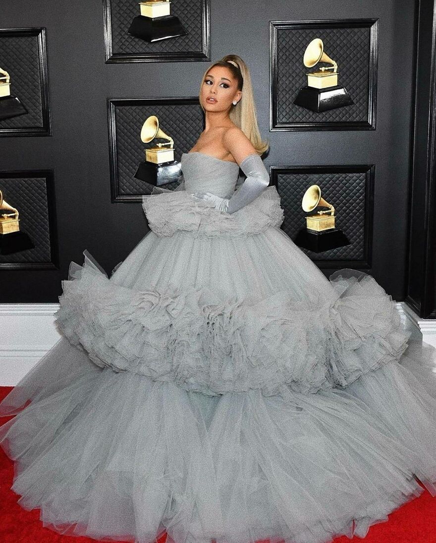 Ariana Grande in a voluminous gray gown and gloves at an event, showcasing a glamorous before and after transformation.
