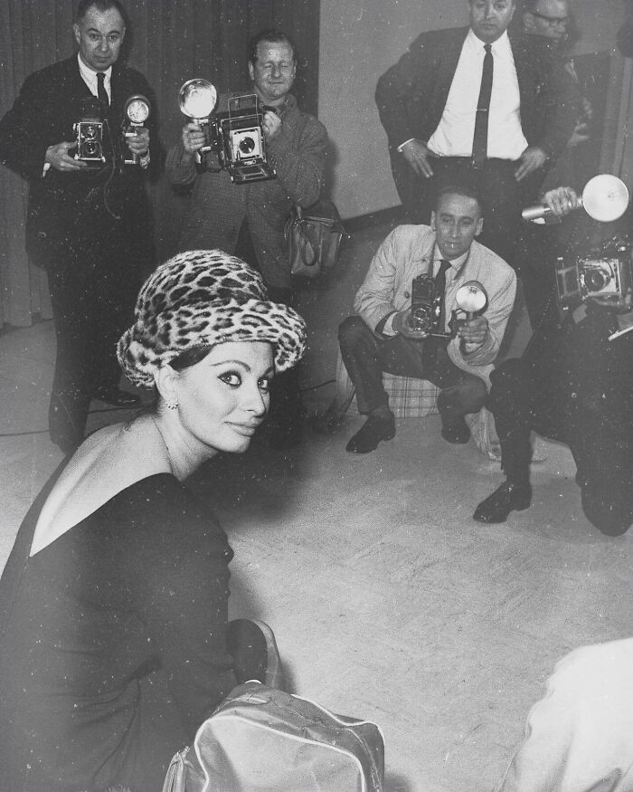 Sophia Loren wearing leopard print hat, surrounded by photographers capturing her Italian beauty and Hollywood legend moments.