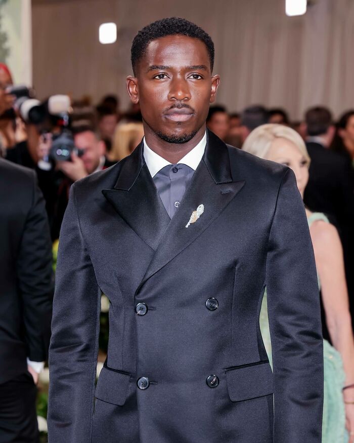 Man in a black double-breasted suit at an event, embodying the most handsome man in the world 2025 style.