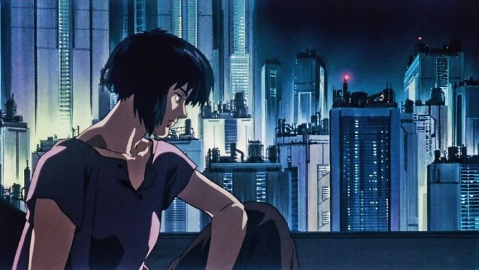Animated woman with short dark hair sitting on rooftop at night in futuristic city, illustrating unrealistic women movie tropes.