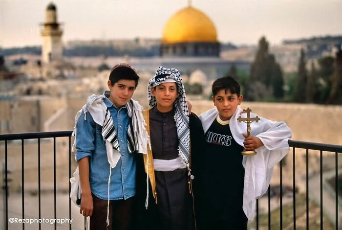 Three boys in traditional clothing posing in front of the Dome of the Rock, part of the most fascinating photos collection.