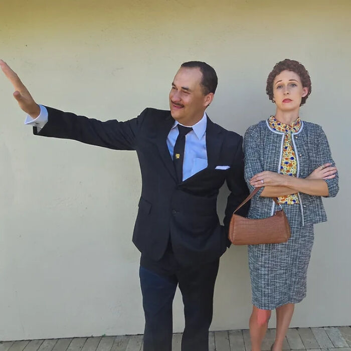 Man transforming into Tom Hanks wearing a black suit and woman standing beside him in vintage attire with a brown handbag.