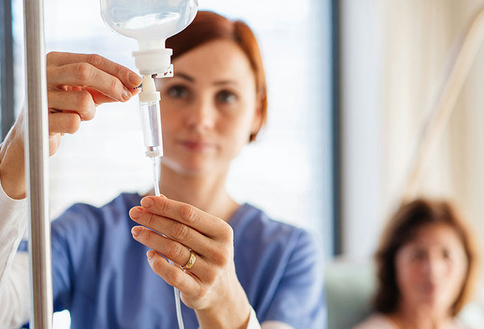 Nurse adjusting IV drip for patient in hospital, illustrating cases of self-diagnosed conditions confirmed later.