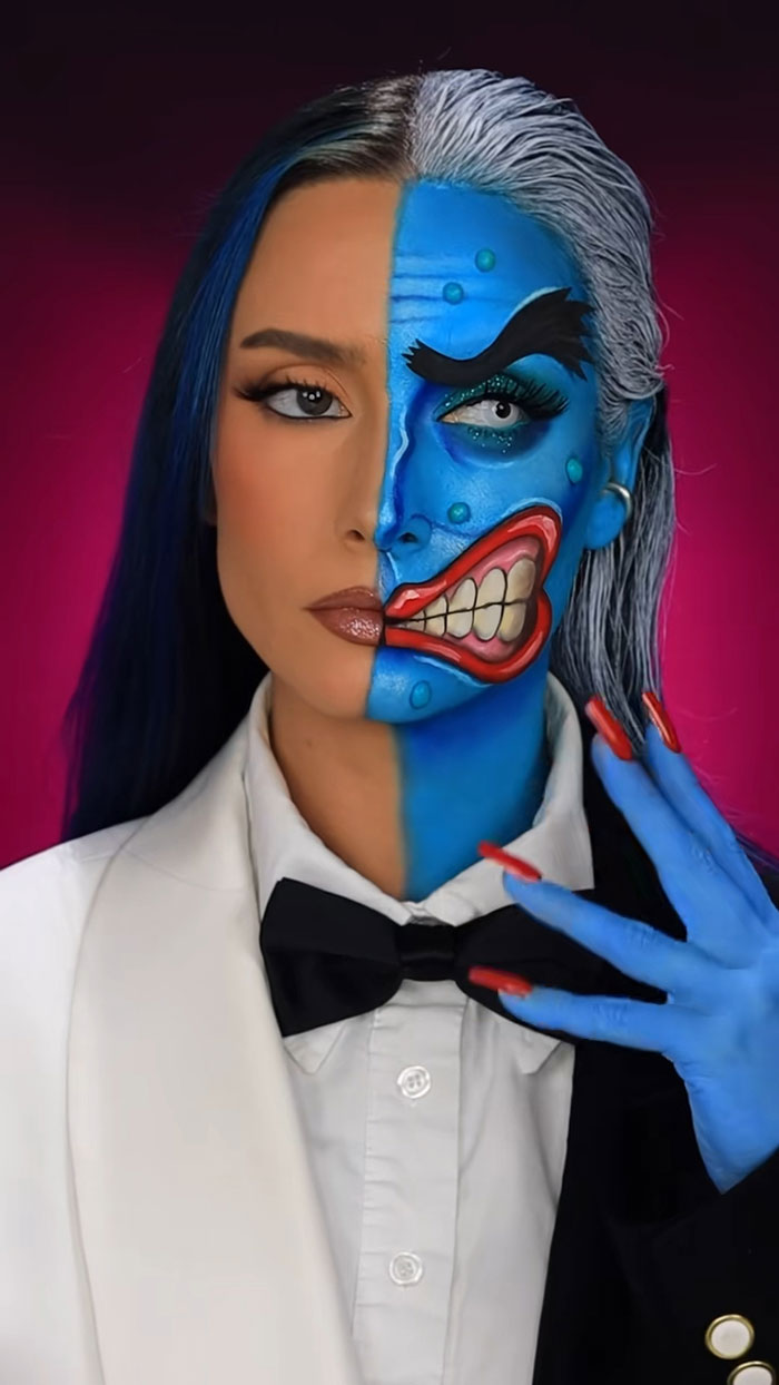 Split face portrait showing creative Halloween makeup with vibrant blue and red details and matching nail art on one side.