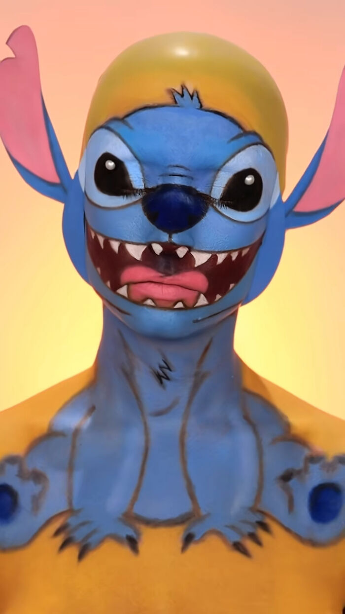 Creative Cliche Halloween makeup transforming a person into a detailed blue cartoon character with large eyes and sharp teeth.