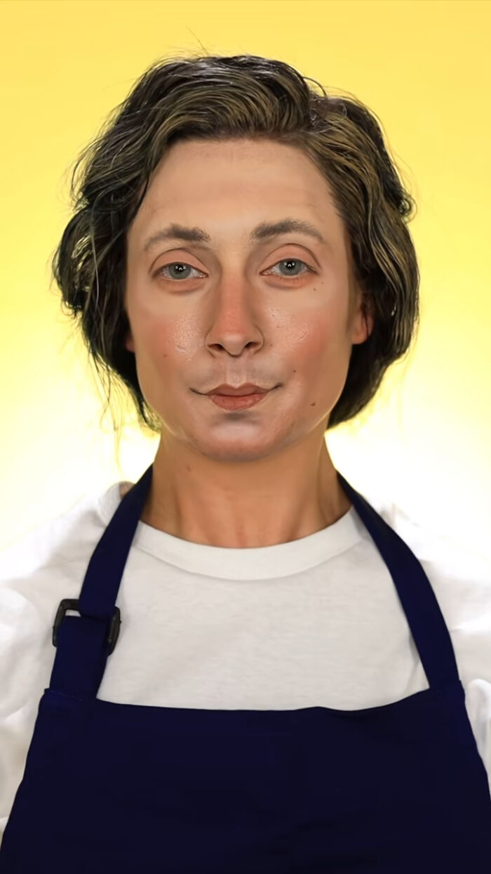 Person wearing detailed Halloween makeup and a dark apron against a yellow background showcasing creative Halloween makeup art.