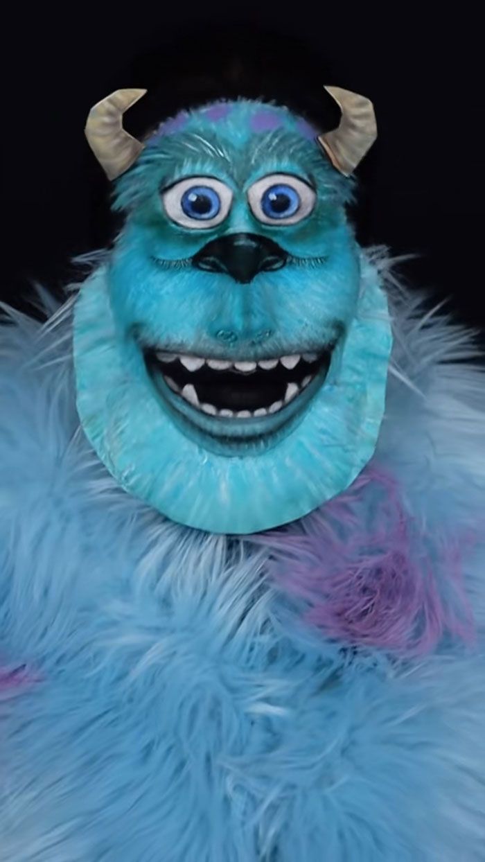 Halloween makeup of a character with blue fur, large eyes, horns, and a wide mouth showing teeth by Creator Creative Cliche.