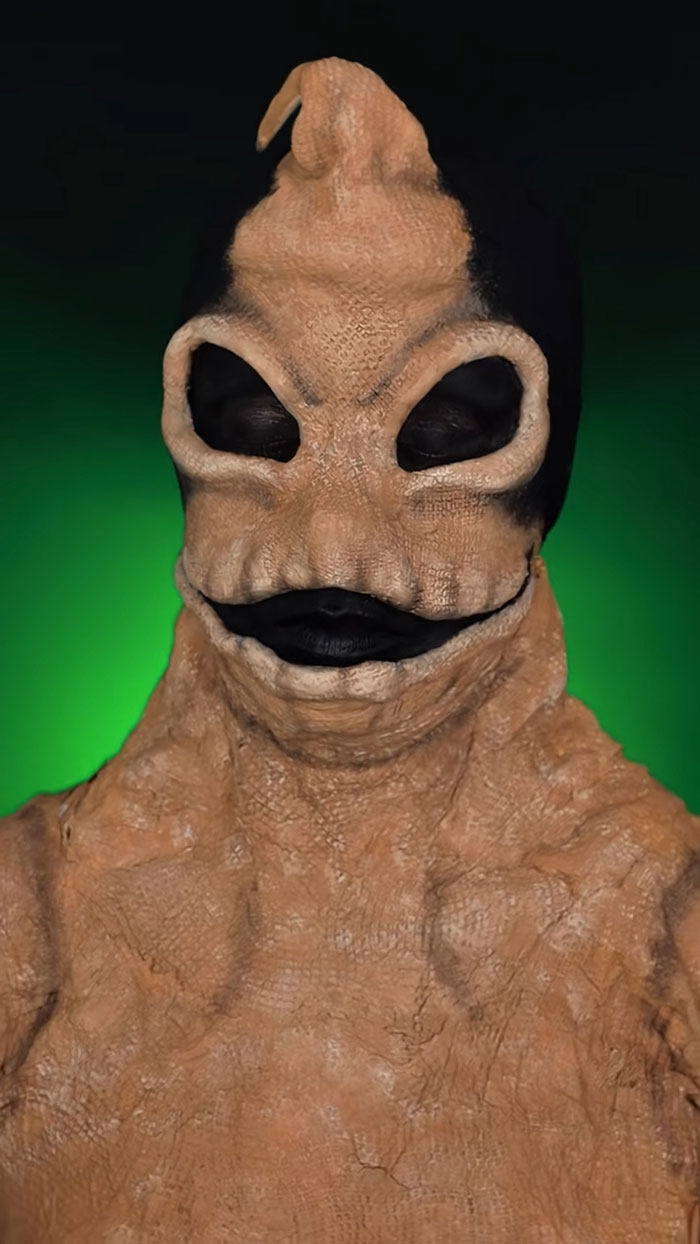 Halloween makeup by Creator Creative Cliche showing detailed textured alien-like character with black eyes and lips on green background