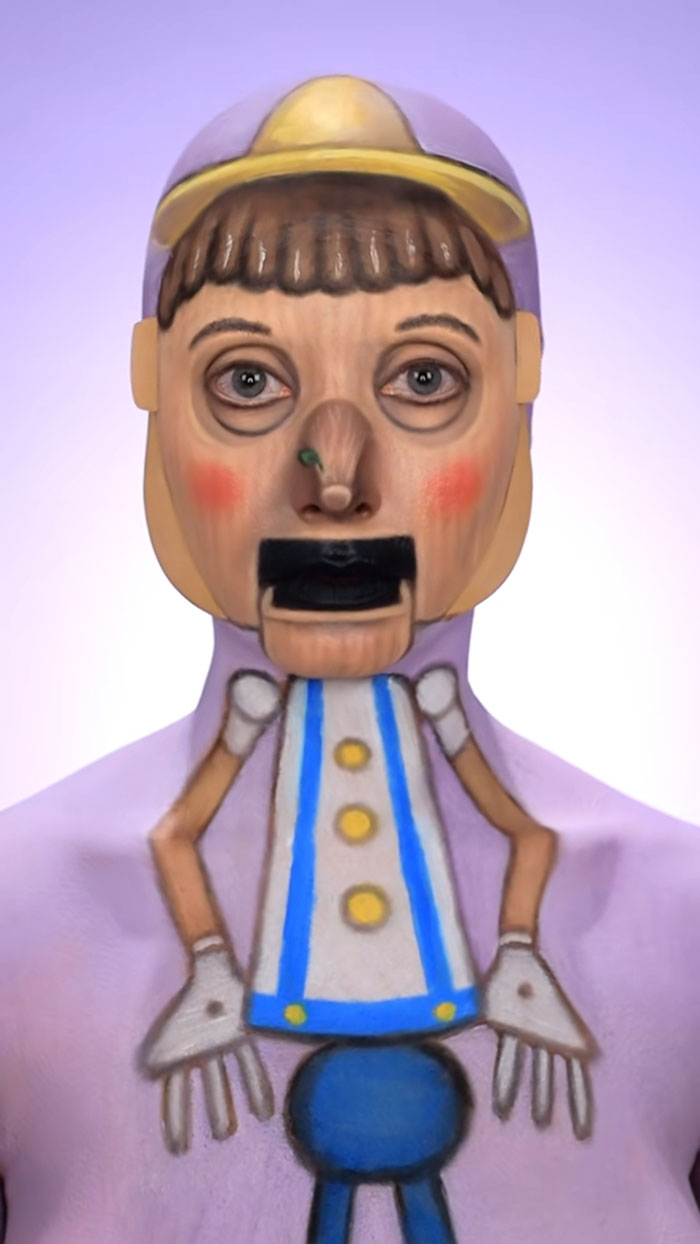 Creative Halloween makeup transforming a person into a detailed wooden puppet character with painted features and costume.