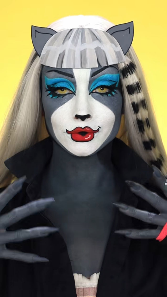 Creative Cliche’s amazing Halloween makeup features a cartoon-style cat face with vibrant blue eyeshadow and red lips.