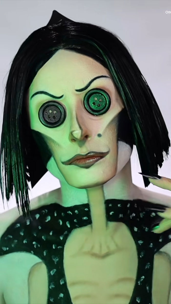 Halloween makeup by Creator Creative Cliche featuring a character with button eyes, black hair, and green-toned skin effects.