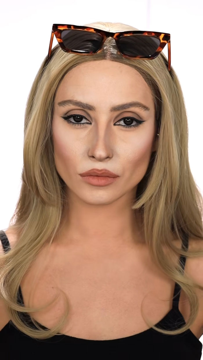 Close-up portrait of woman with Halloween makeup, blonde hair, and sunglasses on head showcasing creative cliche style.