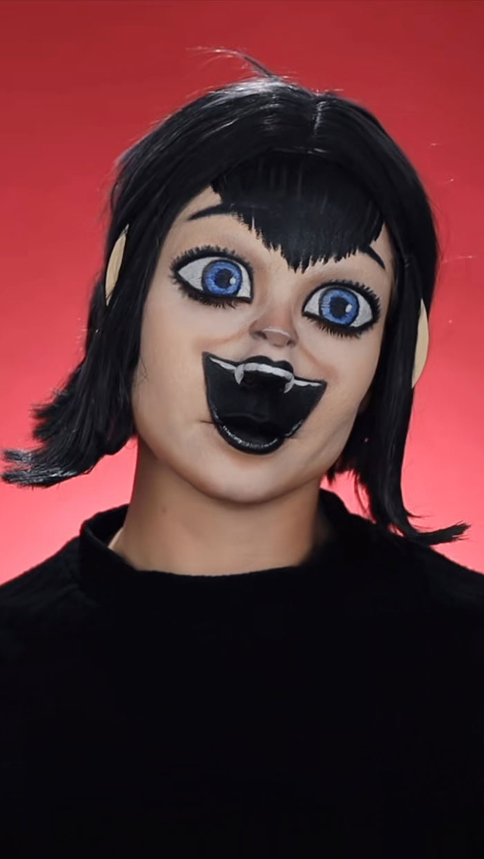 Halloween makeup by Creative Cliche featuring exaggerated cartoonish vampire face with large blue eyes and black hair.