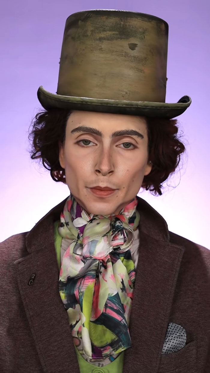 Person wearing detailed Halloween makeup with vintage costume including top hat and colorful scarf against purple background