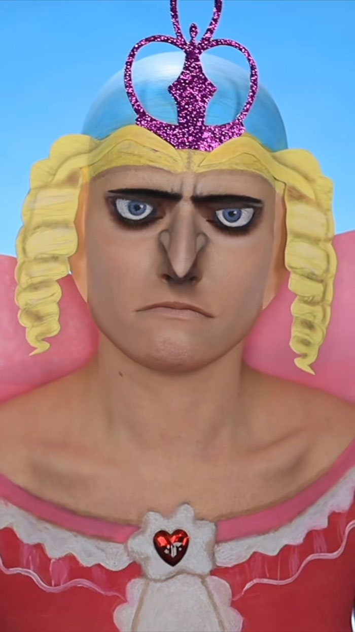 Person with creative Halloween makeup portraying an intense character wearing a glittery crown and blonde curls.