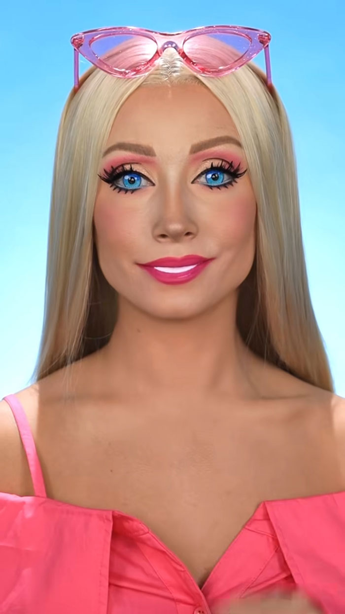 Woman with blonde hair and bright blue eyes wearing creative Halloween makeup and pink sunglasses on head.