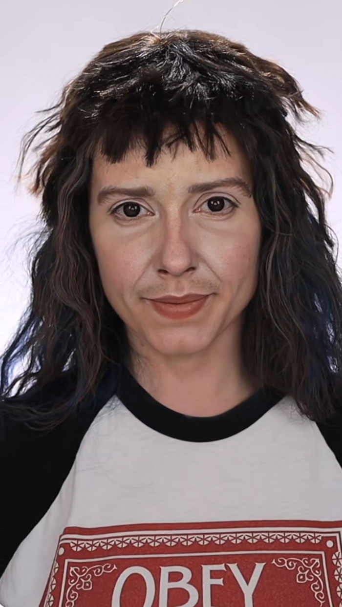 Person with detailed Halloween makeup, styled hair, and wearing a black and white shirt with a red design.