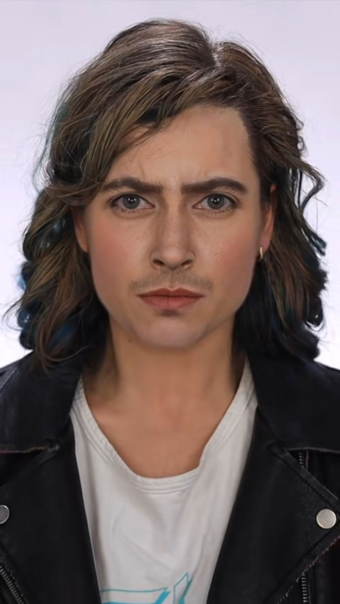 Person with detailed Halloween makeup featuring subtle facial hair, styled hair, white shirt, and black leather jacket.