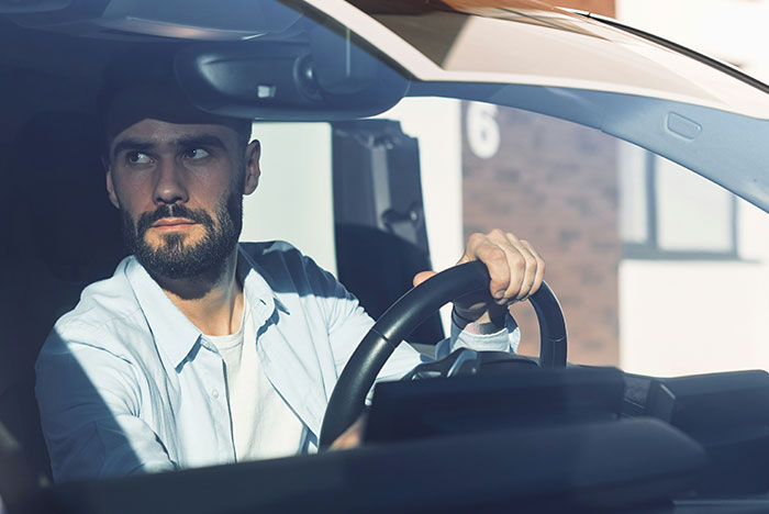 Man with serious expression driving a car, illustrating a moment of instant karma serving people what they deserved.