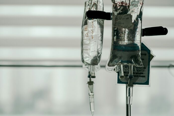 IV bags hanging with fluid tubes in a medical setting, illustrating strange and dumb health hacks from patients.