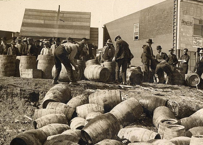 Group of men rolling and inspecting wooden barrels outdoors in a vintage scene related to Rihanna slapped him fascinating facts.