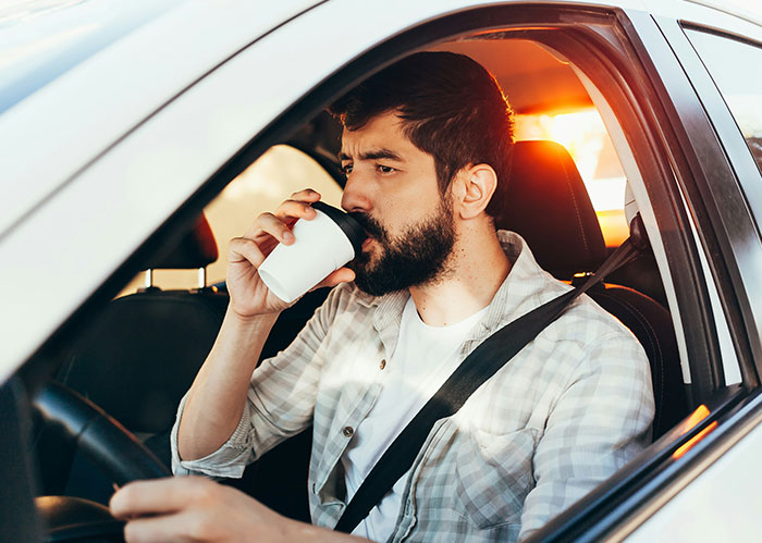 Man drinking coffee inside a car during sunset, illustrating a calm moment related to Rihanna slapped him fascinating facts.