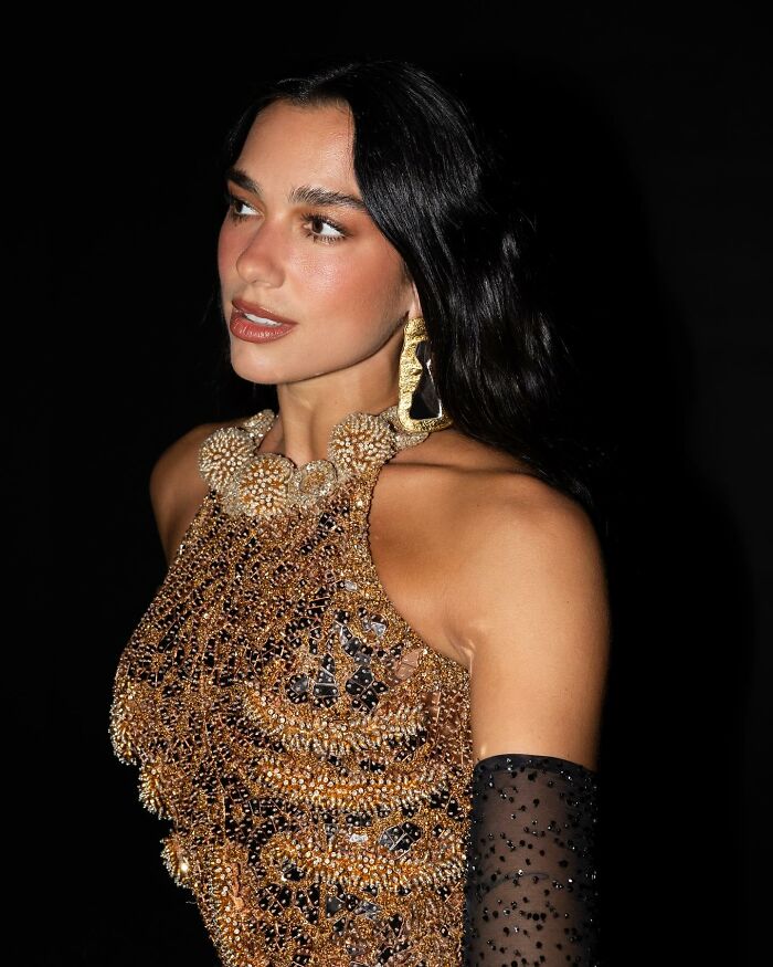 Dua Lipa wearing a detailed gold outfit and statement earrings, amid massive outrage over viral concert video incident. Dua Lipa wearing a detailed gold outfit and statement earrings, amid massive outrage over viral concert video incident.