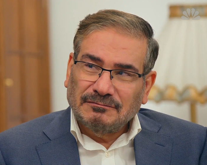 Middle-aged man wearing glasses and a blue suit in an indoor setting, related to risqu&eacute; wedding dress controversy