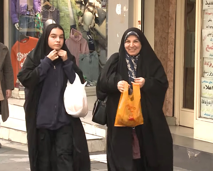 Two Iranian women wearing headscarves walk down a street, highlighting issues of headscarf surveillance and social norms.