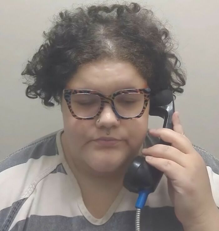 Plus-size activist with curly hair and glasses talking on a phone, seen during a calm moment after an alleged run-in with law. Plus-size activist with curly hair and glasses talking on a phone, seen during a calm moment after an alleged run-in with law.