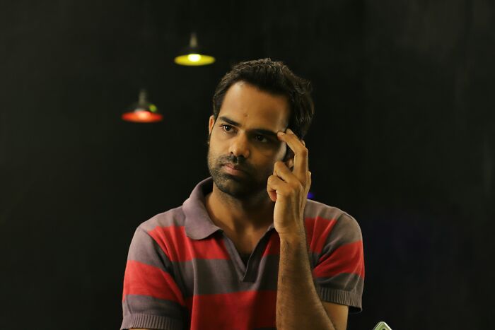 Man in red and gray striped shirt appearing thoughtful and reflective about heartbreaking things committed by close friends.