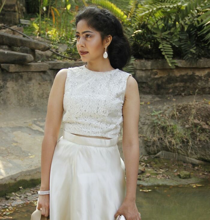 Bride wearing white elegant dress outdoors by a garden, reflecting on wedding guests who made the bride and groom regret it.