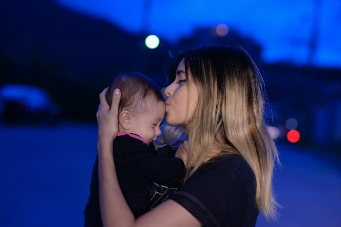 Woman holding and kissing baby outdoors at dusk, illustrating the theme of highly disturbing things folks were told.
