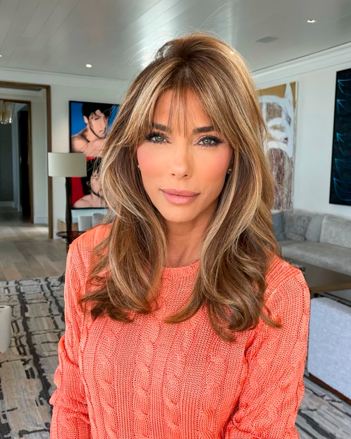 Sylvester Stallone&rsquo;s wife in an orange sweater posing indoors amid modern art and stylish home decor.