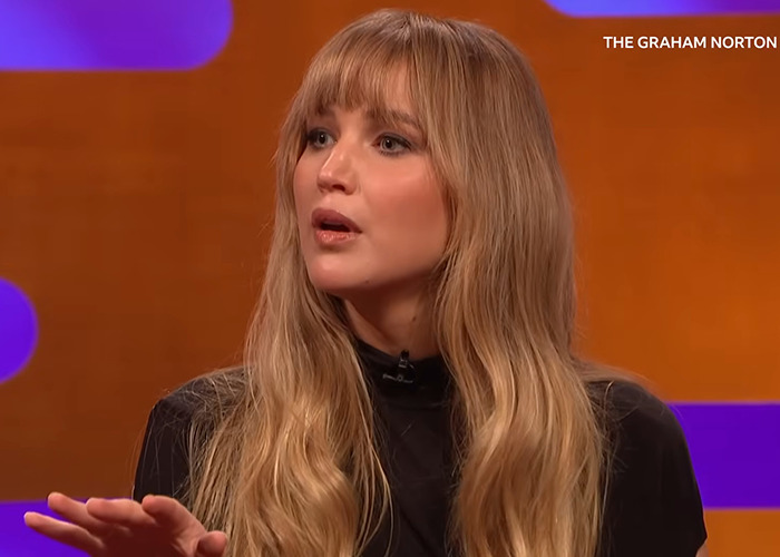Jennifer Lawrence reacting during a heated discussion on The Graham Norton Show with a focused expression and hand gesture