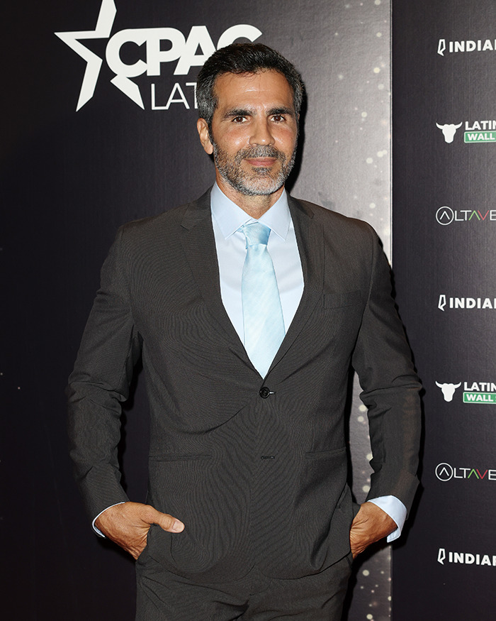 Man in dark suit and light blue tie posing at CPAC Latino event with Jennifer Lopez ex-husband cheating Instagram rant theme.