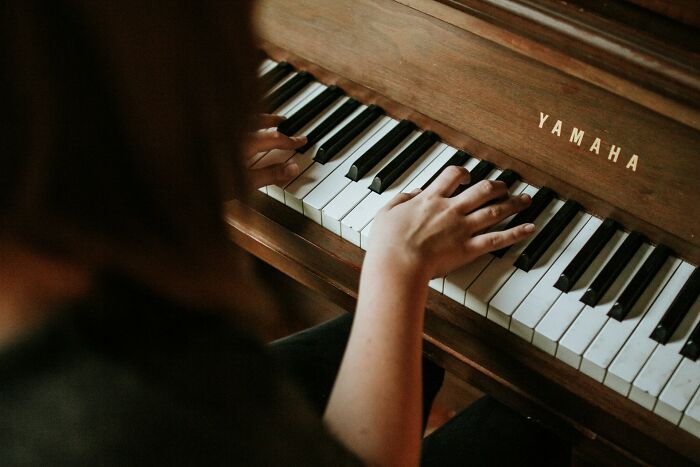 Person playing a Yamaha piano, illustrating the concept of dark secrets that could ruin people’s lives if revealed.