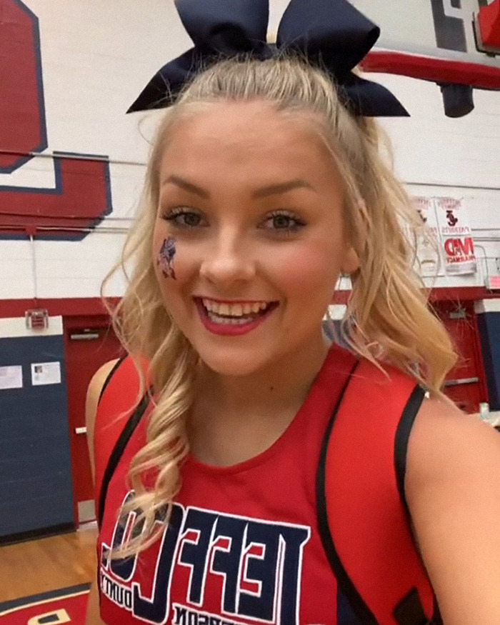 Young woman with a large bow and face paint inside a gym, related to the Laken Snelling baby case controversy.