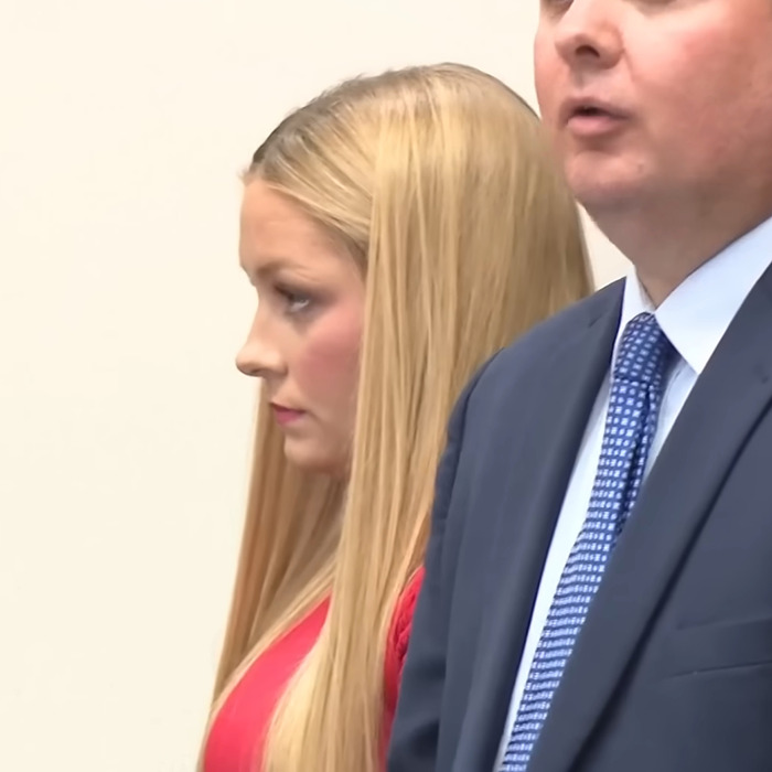 Woman with long blonde hair in red dress standing beside man in suit during legal proceedings related to Laken Snelling baby case.