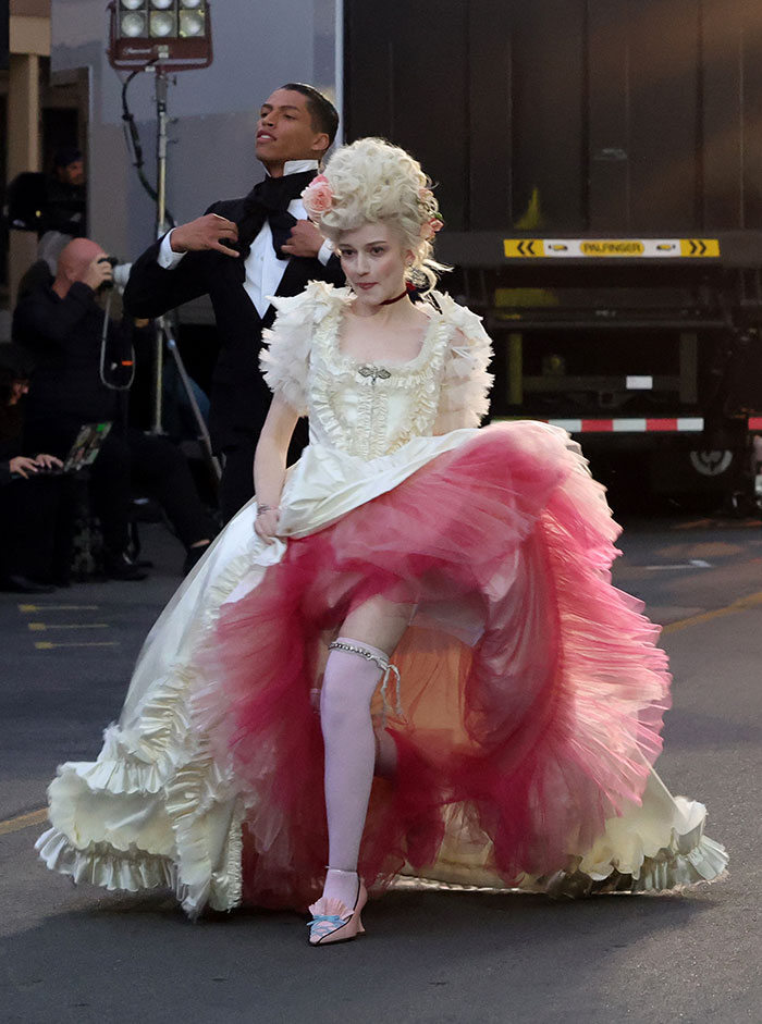Celebrity in a vintage-inspired white and pink dress with elaborate hairstyle, one of the worst and weirdest Vogue World Hollywood looks.