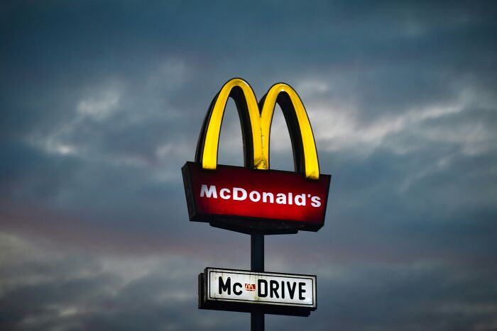 McDonald’s brand sign glowing at dusk with dark cloudy sky, illustrating popular internet brand descriptions.