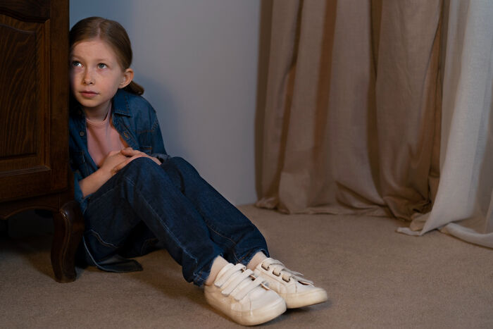 Young girl sitting on the floor looking anxious, illustrating moments when people were told they were just anxious.