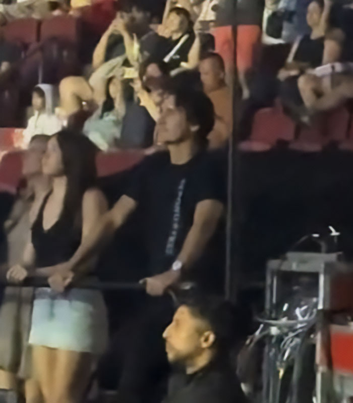 Couple holding hands at an event with a crowd in the background, hinting at Katy Perry and Justin Trudeau romance news.