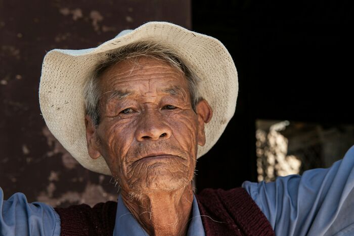 Elderly Chinese man wearing a white hat and a blue shirt.
