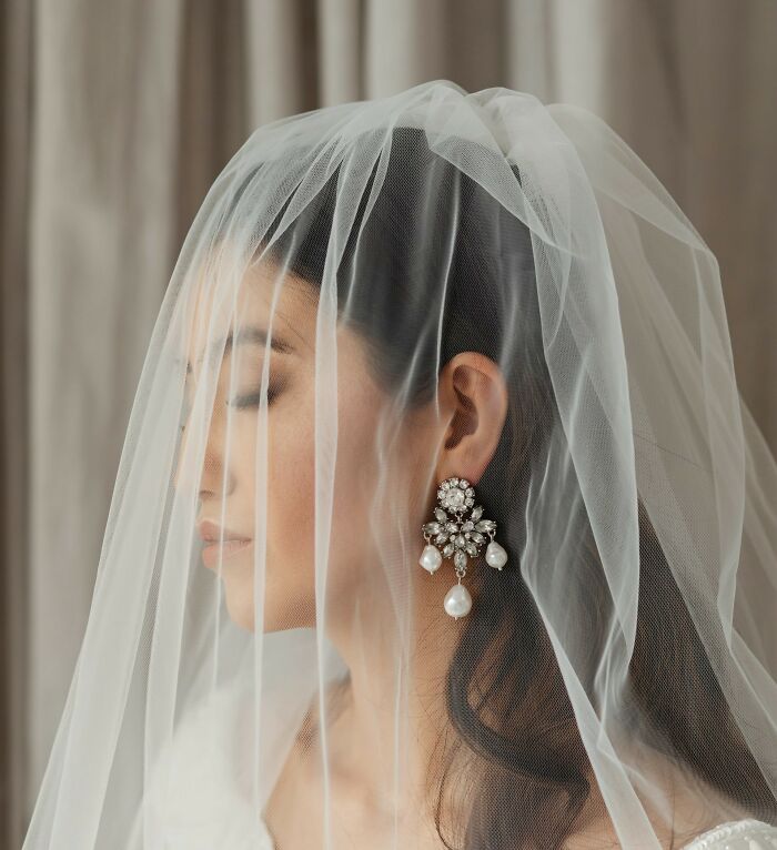 Bride wearing pearl earrings and a veil, representing a wedding guest moment that made the bride and groom regret.