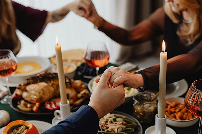 Couple holding hands at a dinner table with food and candles, capturing a moment related to raisin potatoes.