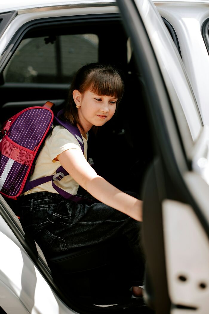 Young girl with a backpack sitting in a car, reflecting on heartbreaking things committed by close friends that broke trust forever.