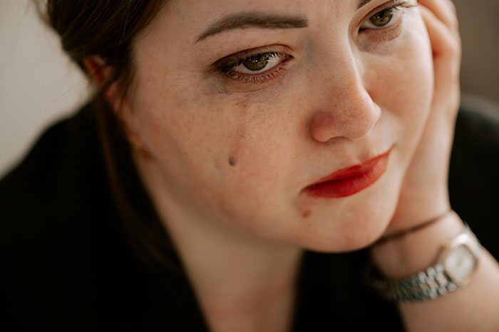 Close-up of a distressed woman with red lipstick, resting her face on her hand, reflecting on her miracle baby situation.
