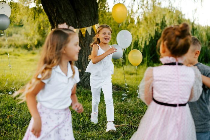 Children playing happily outdoors at a wedding, surrounded by balloons as wedding guests celebrate the special day.