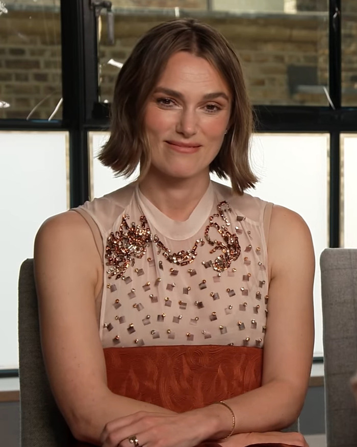Keira Knightley seated indoors wearing a sleeveless embellished top amid Harry Potter casting backlash discussion.